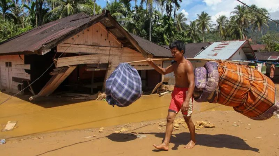 Warga memanggul barang-barang miliknya saat melintas di area banjir bandang dan longsor di Kelurahan Huta Nabolon, Kecamatan Tukka, Kabupaten Tapanuli Tengah, Sumatera Utara, Rabu (03/12).